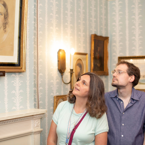 Two people admire a portrait of Catherine Dickens